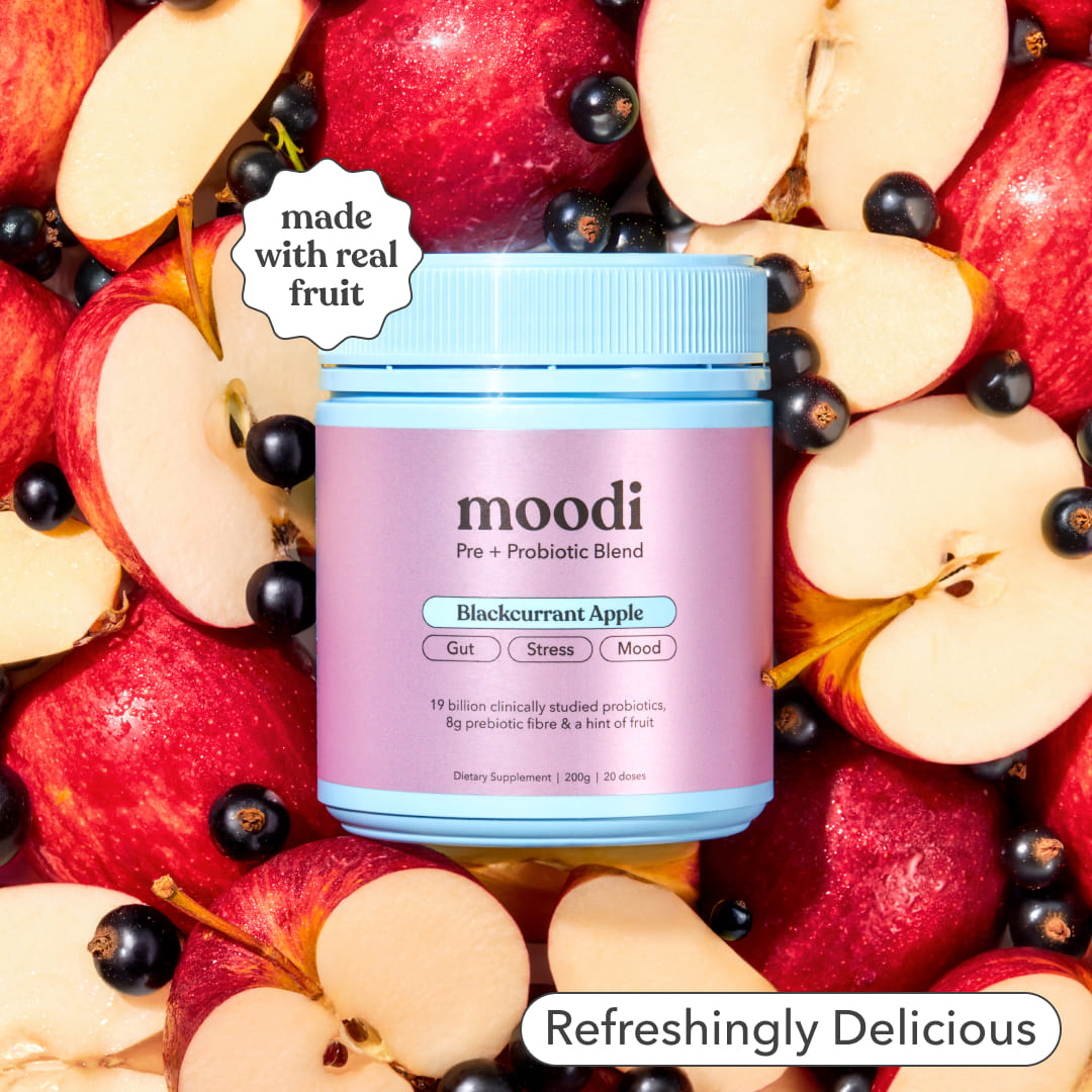 Moodi Blackcurrant Apple pre + probiotic tub surrounded by sliced apples and blackcurrant