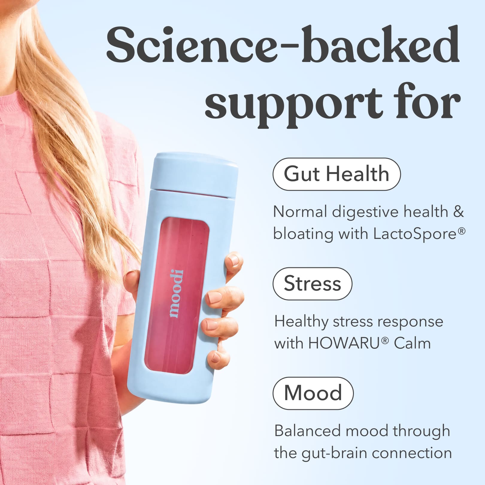 Person holding Moodi's drink bottle with Pink Lemonade, with text promoting gut health, stress and mood support on a light blue background.