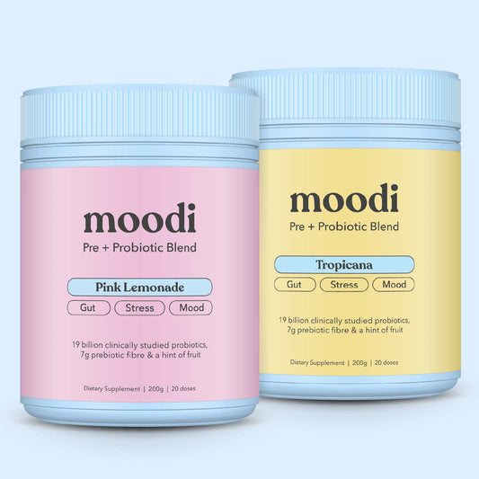 Two jars of moodi pre + probiotic blend, one pink lemonade and one tropicana, on a light blue background.