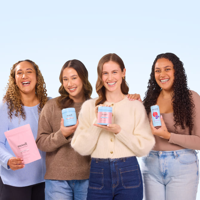 Four women holding Moodi products against a light blue background