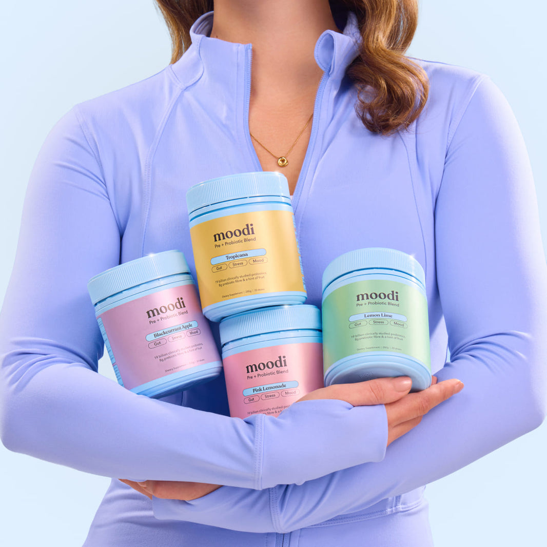 Person holding four tubs of moodi products against a light blue background