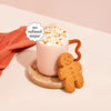 A mug of Moodi Gingerbread with whipped cream and a gingerbread man cookie