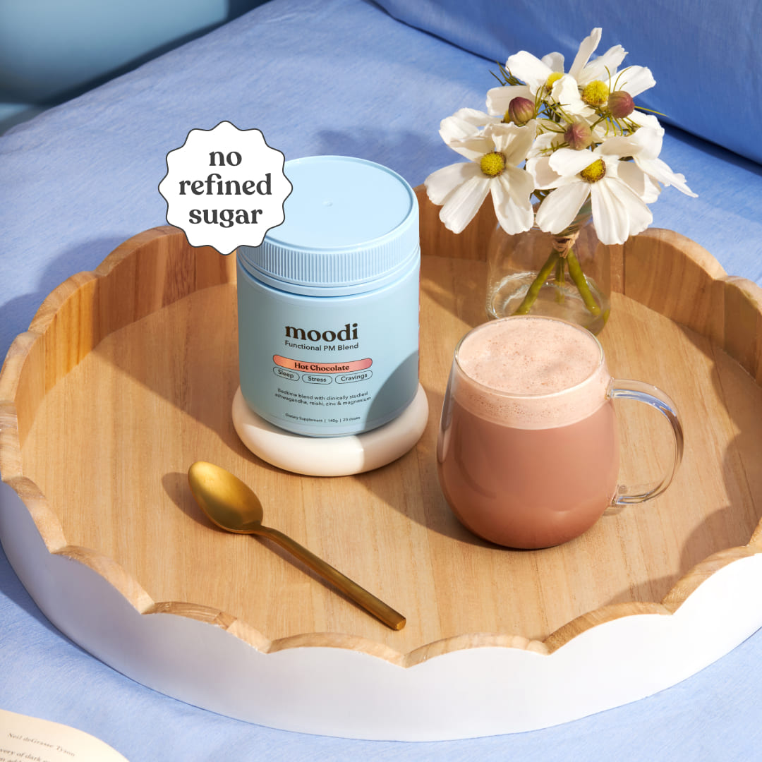 Moodi Hot Chocolate tub and hot drink on a wooden tray with a spoon and flowers