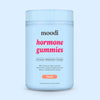 Container of moodi Peach Hormone Gummies on a light blue background