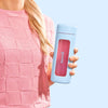 A woman in a pink textured sweater holds a light blue mood tumbler with a pink window and the word 'moodi' printed on it, set against a solid light blue background.