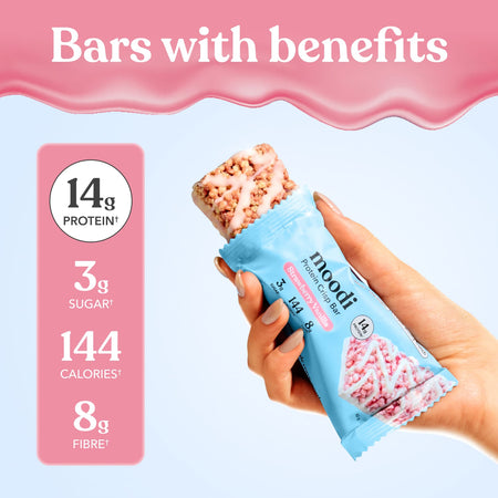 Hand holding a protein bar with nutritional information displayed on a pink and blue background
