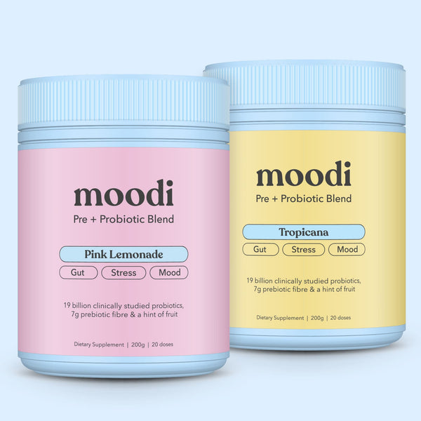 Two jars of moodi pre + probiotic blend, one pink lemonade and one tropicana, on a light blue background.