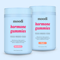 Moodi strawberry and peach hormone gummies tubs on a light blue background