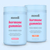 Moodi strawberry and peach hormone gummies tubs on a light blue background